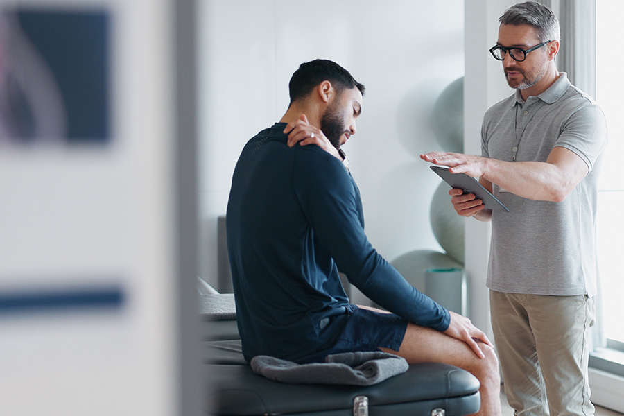 Physiotherapy, tablet and shoulder pain with people in clinic for rehabilitation, healthcare or consulting.