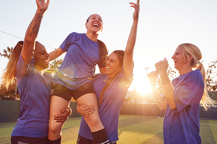 teenaged girls celebrating in soccer team uniforms